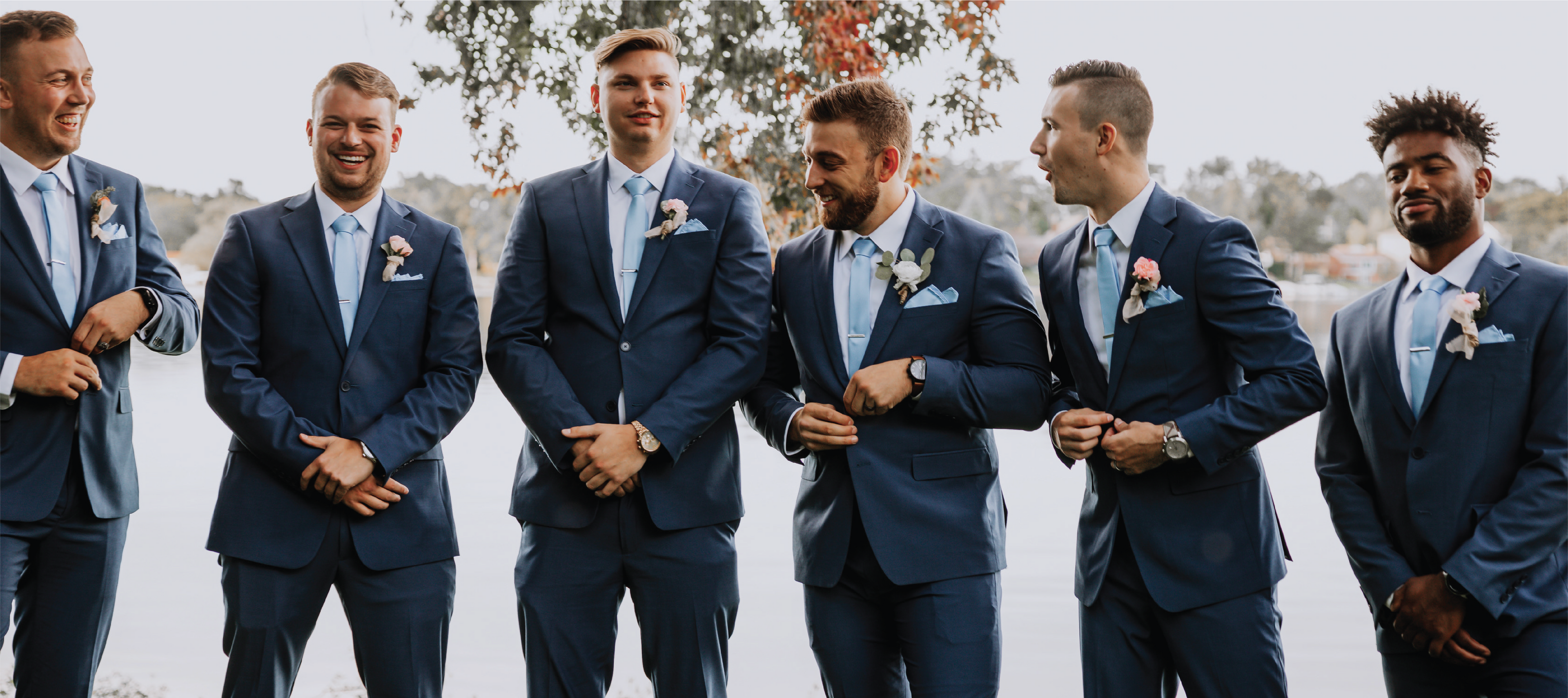 Happy, well dressed groomsmen in blue two piece suits, white shirts and light blue tie and hanky sets.