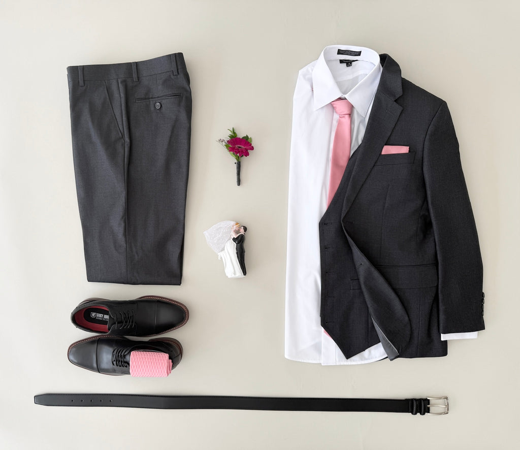 Studio shot charcoal grey vested (optional) suit, white dress shirt, champagne colored tie and pocket square, black dress shoes, with champagne socks, and black belt.