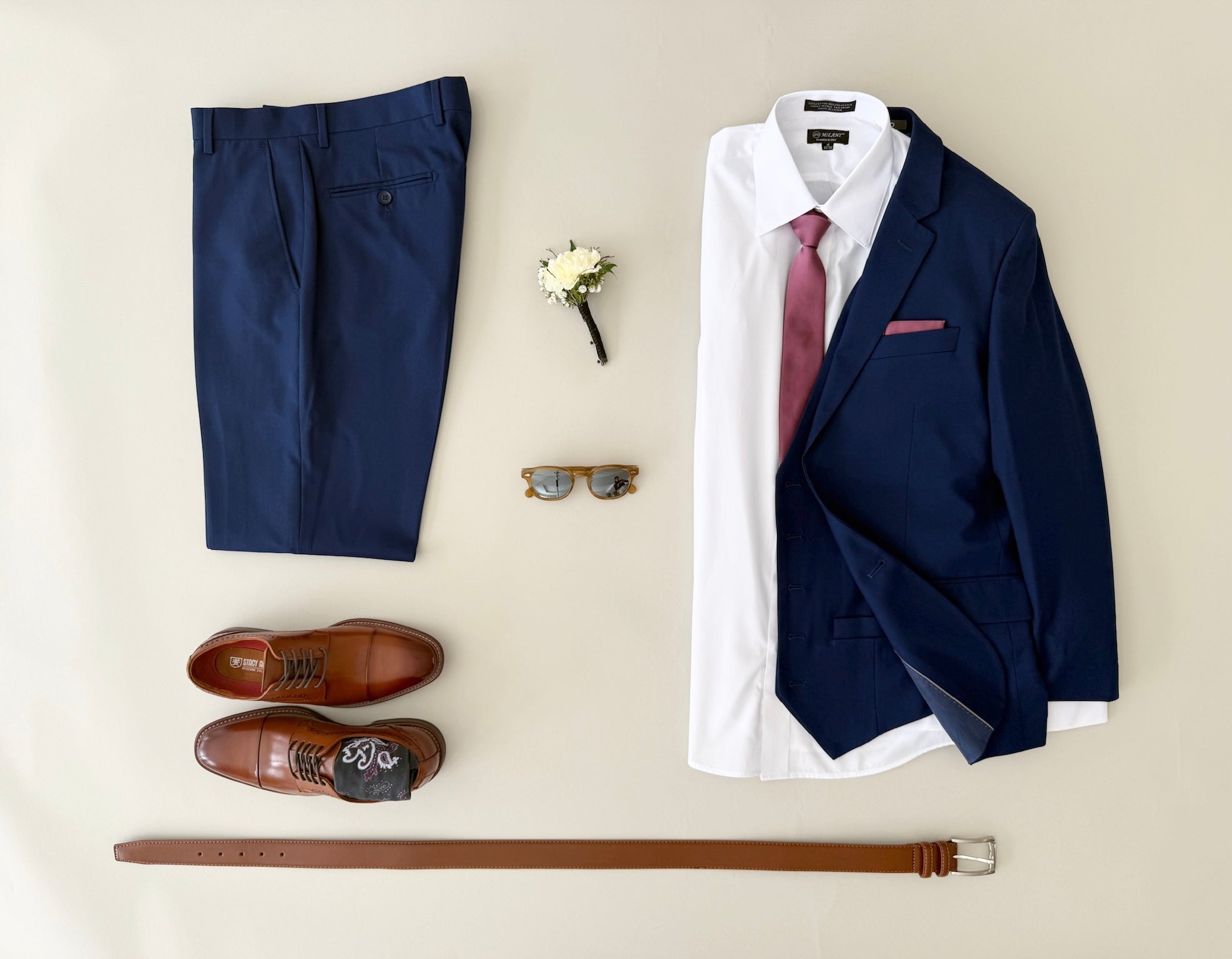 Studio image of cobalt blue vested suit, white dress shirt, tie and pocket square, cognac shoes and cognac belt.