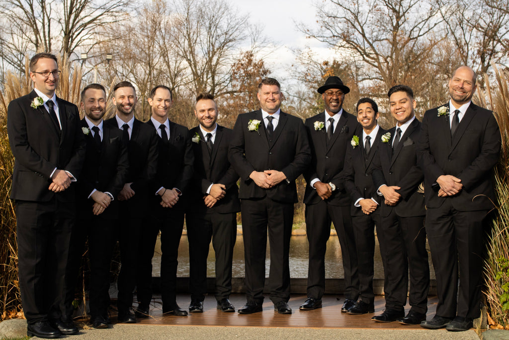 Groom and his 9 groomsmen all wearing black vested suits, white dress shirts and black ties.