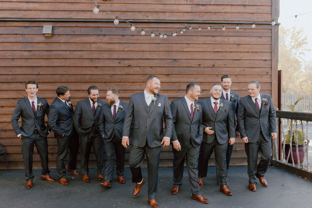 Groom and his 8 groomsmen all wearing the vested charcoal grey suit, white shirt either a white tie (groom) or burgundy tie for groomsmen and cognac dress shoes.