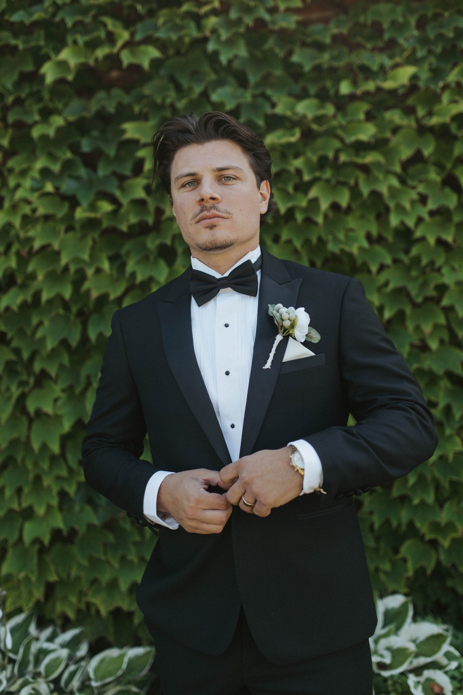 Groom wearing a classic black tuxedo with peak lapels, formal shirt, bowtie, cufflinks and studs.