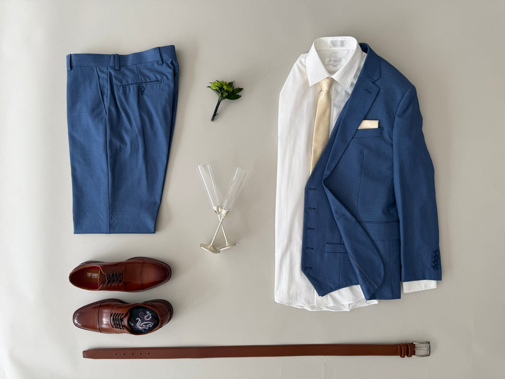 Groom's outfit with blue suit, white shirt, brown shoes, and accessories on a light gray background