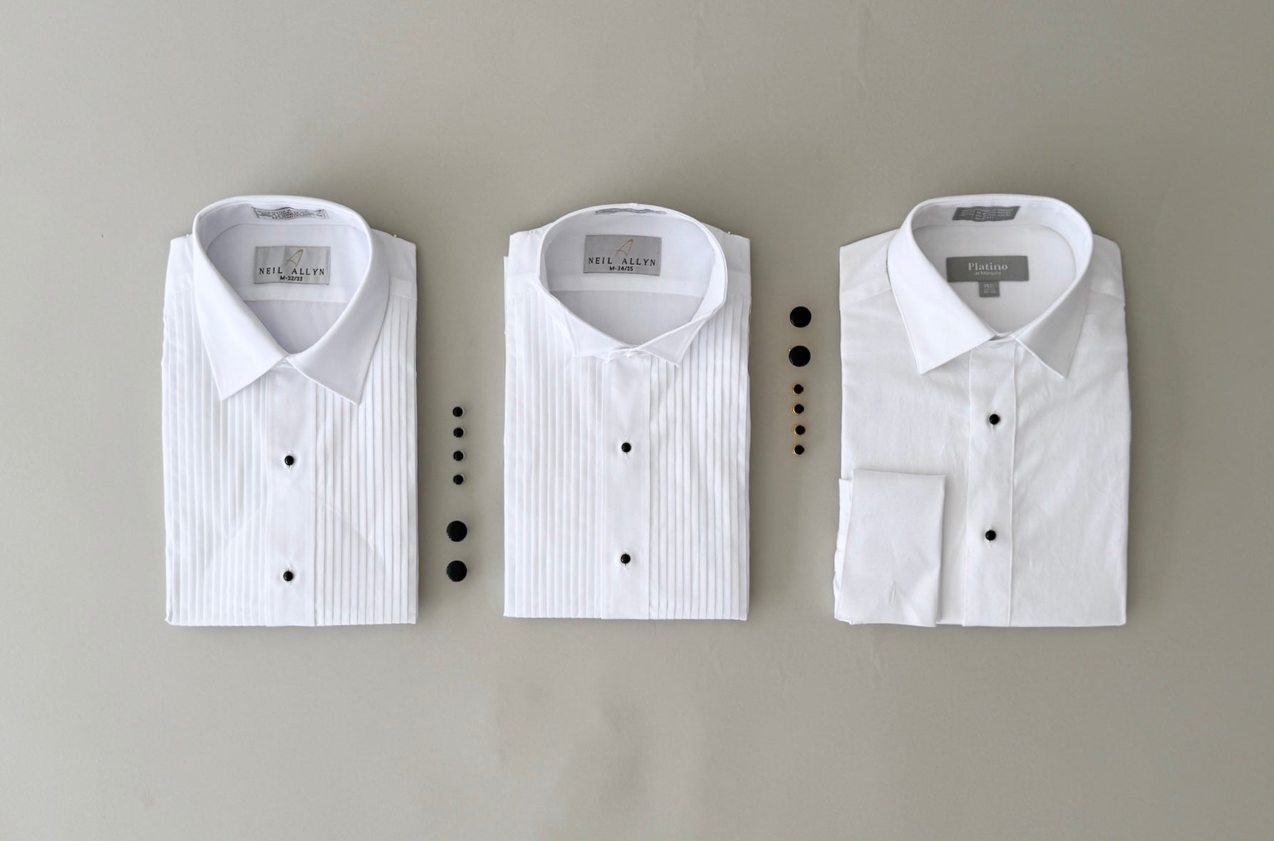 Three white tuxedo shirts. Laydown collar pleated shirt, wing collar pleated shirt, and a no-pleat french cuff tuxedo shirt.