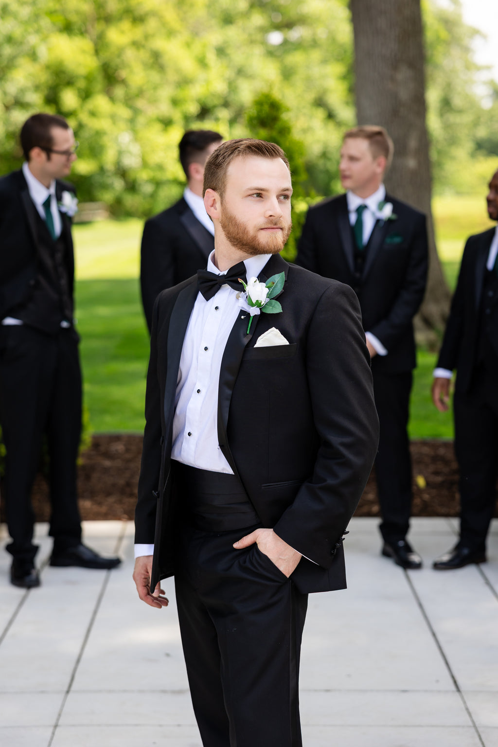 Groom in a timeless black notch lapel tuxedo, black bowtie and cummerbund, laydown formal shirt.